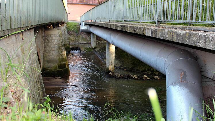 Die Leitungen für Wasser, Gas und Strom an der Unterseite der Fußgängerbrücke werden während der Neubauphase provisorisch an die Kreisstraßenbrücke (links) angeheftet und anschließend wieder zurückverlegt. Foto: Pfannes