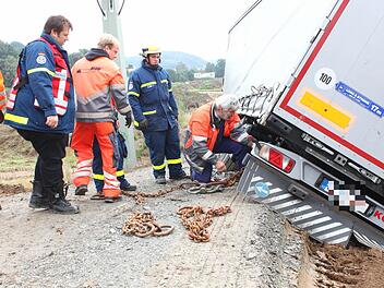 Mit Eisenketten versuchen die Helfer, den Lastwagen, der sich mittlerweile gefährlich geneigt hat, zu sichern. Foto: Katrin Geyer