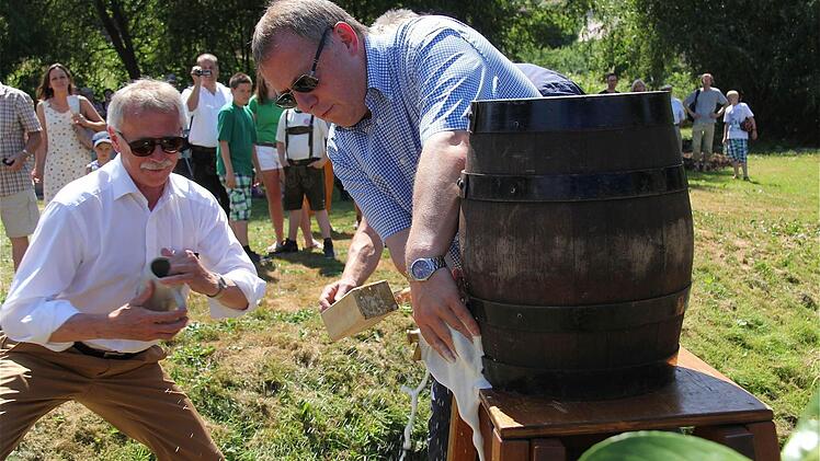 Ernst Stross (SPD, links) springt Schirmherr Landrat Thomas Bold (CSU) beim Bieranstich helfend zur Seite.