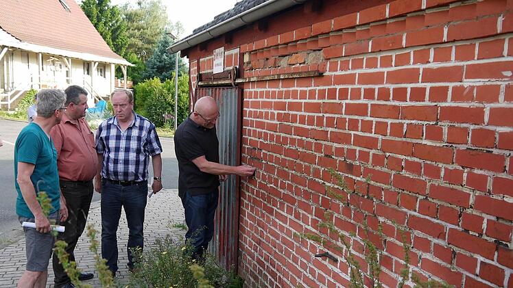 Da bröckelt der Putz: Während Gemeinde-Geschäftsleiter Dieter Scherbel dem Zustand der Mauerfugen auf den Grund geht, diskutieren Werner Thomas, Gerald Oehrl und Rudolf Stöckert (von rechts) über die finanziellen Fragen. Foto: Berthold Köhler