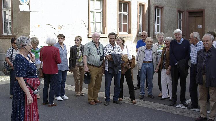 Stadtführerin Eva Albert (l.) informiert die Schulkameraden im ehemaligen Pausenhof über den heutigen Verwendungszweck ihres Schulhauses. Foto: Winfried Ehling