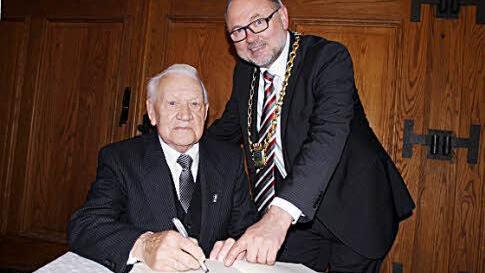 Adam Göller trug sich ins "Goldene Buch" der Stadt Ebern ein. Bürgermeister Robert Herrmann (rechts) würdigte ihn als Vorbild für andere.  Foto:   Kiesewetter