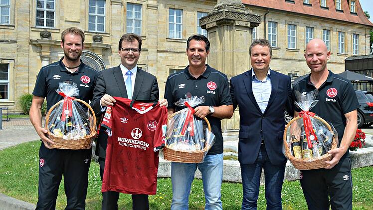 Mit einem von den Spielern signierten Trikot revanchierten sich Coach Alois Schwarz (Mitte) und seine Co-Trainer bei B&uuml;rgermeister Christian Lange f&uuml;r das Bamberger Biergeschenk. Foto: Stadt Bamberg, Pressestelle