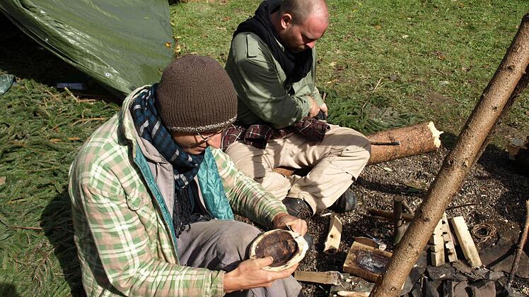 Tobias Krüger (links) zeigt, wie aus einem Stück Holz durch Schnitzen und Ausbrennen ein Teller oder eine Schale wird. Fotos: Susanne Deuerling