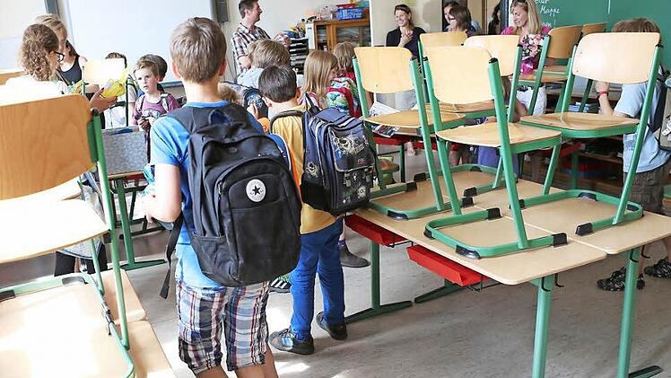 Stühle hoch! Schüler einer vierten Klasse verabschieden sich an ihrem letzten Schultag vor den Sommerferien von ihrem Klassenlehrer. Alle Schüler gehen weg und besuchen verschiedene weiterführende Schulen.   Foto: Christian Charisius/dpa