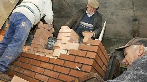 Josef Schmitt, Gottfried Schneid und Karl Popp (von links) mauern den Backofen.