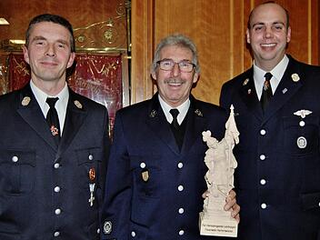 Mit einer Holzskulptur des Heiligen Florian für besondere Leistungen im Verein bedankten sich Kommandant Bernd Ort (links) und sein Stellvertreter Tobias Dittrich (rechts) bei Feuerwehrmann Rudolf Kiesel (Mitte) und verabschiedeten ihn zugleich nach 44 Jahren aus dem aktiven Dienst  Foto: Sigismund von Dobschütz
