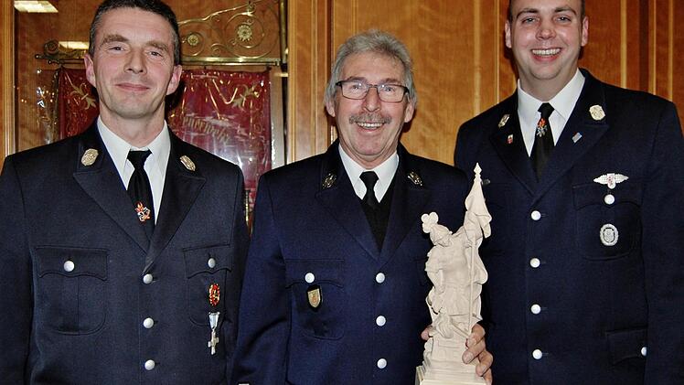 Mit einer Holzskulptur des Heiligen Florian für besondere Leistungen im Verein bedankten sich Kommandant Bernd Ort (links) und sein Stellvertreter Tobias Dittrich (rechts) bei Feuerwehrmann Rudolf Kiesel (Mitte) und verabschiedeten ihn zugleich nach 44 Jahren aus dem aktiven Dienst  Foto: Sigismund von Dobschütz