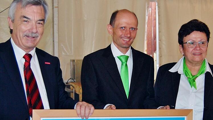 Rolf Lauer, Hauptgeschäftsführer der Handwerkskammer Unterfranken, übergibt zum Jubiläum ein Poster an Michael Albert und Seniorchefin Hilda Albert