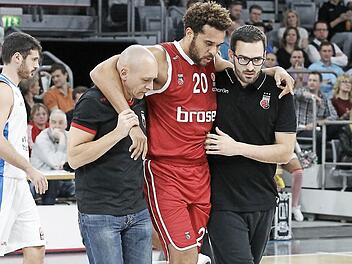 Teamarzt Andreas Först (l.) und Physiotherapeut Heiko Pfister (r.) stützen den verletzten Elias Harris auf dem Weg in die Kabine. Foto: sportpress