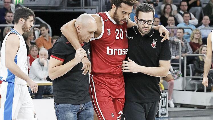 Teamarzt Andreas Först (l.) und Physiotherapeut Heiko Pfister (r.) stützen den verletzten Elias Harris auf dem Weg in die Kabine. Foto: sportpress