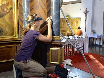 Expertin Annegret Schwarz arbeitet, mit Lupenbrille und Skalpell ausgestattet, an einer Säule des Marienaltars in der Burkardrother Pfarrkirche. Foto: Kathrin Kupka-Hahn