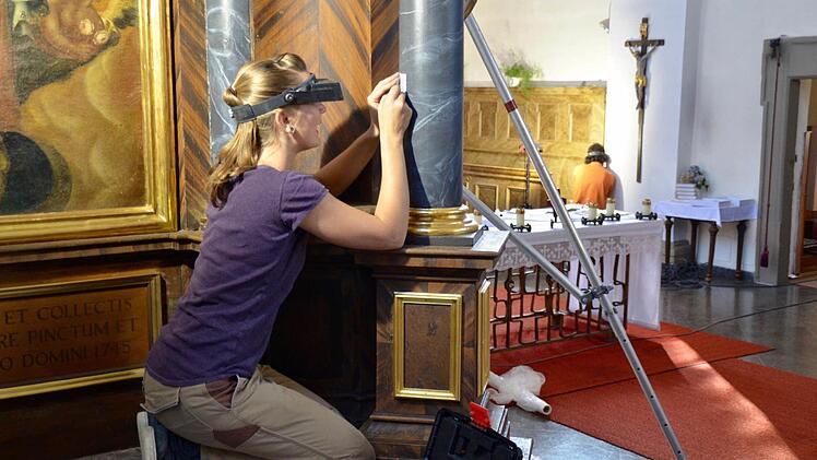 Expertin Annegret Schwarz arbeitet, mit Lupenbrille und Skalpell ausgestattet, an einer Säule des Marienaltars in der Burkardrother Pfarrkirche. Foto: Kathrin Kupka-Hahn