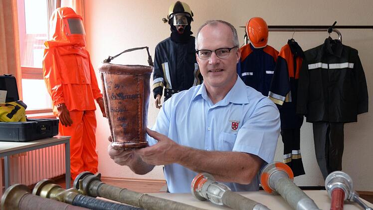 Alte Feuerwehrgerätschaften wurden im Garitzer Schulungsraum gezeigt. Vor der Gründung der Freiwilligen Feuerwehren musste in vielen Orten jeder Mann einen ledernen Löscheimer stellen. Hier zeigt Kommandant Ralf Schubert ein  Exemplar von 1859, davor die  Strahlrohre aus der 150-jährigen Geschichte der Feuerwehr. Peter Rauch