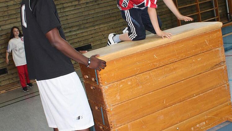 Der Basketballer hilft den Kindern bei den Übungen.