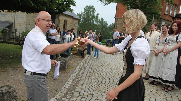 Volker Lauterbach, der Vorsitzende des Förderkreises überreicht den goldenen Lindenschlüssel an Ober-Ortsmadla Marina Ellner. Und die zögert nicht lange und stürmt mit den Ortsburschen die Lindenkrone. Foto: Sonja Adam