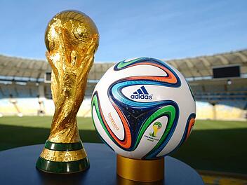 Der WM-Pokal und der offizielle Spielball "Brazuca" warten in Rio de Janeiro auf den Sommer. Foto: dpa/adidas