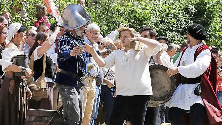 Bei all der Anstrengung hochwillkommen: ein Becher voll Bier. Allerdings müssen die Bräuknechte ihn mit einem Schluck leeren. Viertelmeister Stefan Wicklein, der spätere Sieger, schaut zu (rechts).  Foto: Matthias Hoch