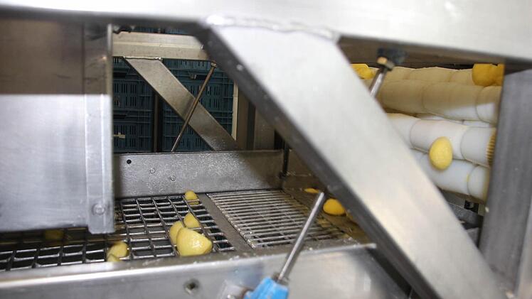 Eine Messer halbiert die gewaschenen und geschälten Kartoffeln.