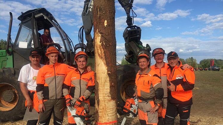 Die Mannschaft aus Weißrussland und einige Junioren der U 24 in Lillehammer mit Trainer Gottl Schwender aus Gräfendorf (rechts) an einem Baumstamm, der gefällt werden soll.  Foto: Sandra Schwender