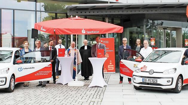 Die &Uuml;bergabe fand vor der Hauptstelle der Sparkasse Forchheim statt (v.&nbsp;l.): Ewald Maier, Romy Heise und Wolfgang Badura (Lebenshilfe Forchheim) mit Berater Florian Hartlieb, Pfarrer Martin Emge und Pfarrer Enno Weidt, Hermann Ulm, Uwe Kirschstein, Walter Horsch und Lukas H&auml;nsch (ASB Forchheim) mit Berater Johannes Stadter.