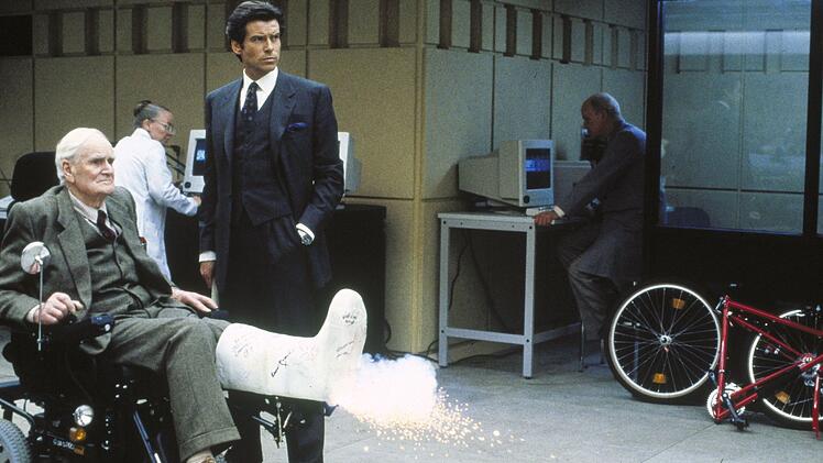 In 17 Bond-Filmen spielte Desmond Llewelyn (links), wie hier in "Goldeneye", den Waffenmeister Q, der James Bond (Pierce Brosnan) mit allerlei hilfreichen, originellen Gadgets ausstattete. 1999 hatte er in "Die Welt ist nicht genug" (1999) seinen letzten Auftritt.