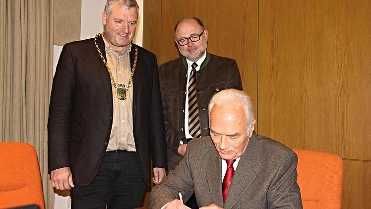 Vor den Augen von Bürgermeister Jürgen Hennemann (links) und dessen Vorgänger im Amt, Altbürgermeister Robert Herrmann (2. von links), trägt sich Franz Geuß in das Goldene Buch der Stadt Ebern ein, wie zuvor auch Altbürgermeister Robert Herrmann. Damit würdigte die Stadt Ebern deren Wirken zum Wohle der Stadt Ebern und die Verleihung der Staatsmedaille für kommunale Verdienste in Bronze, die sie vom Regierungspräsidenten Dr. Paul Beinhofer erhalten hatten. Foto: Helmut Will