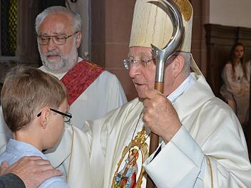Weihbischof Ulrich Boom spendete Benjamin Beck aus Windheim sowie 43 weiteren Firmlingen in der Pfarrkirche St. Trinitas in Aschach das Sakrament der Firmung. Im Hintergrund Diakon Franz Hey.  Foto: B. Hein