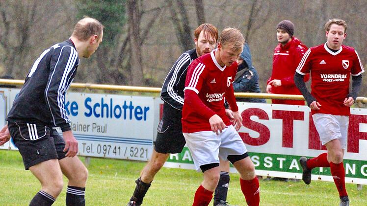 Der Obererthaler Christof Rüth (schwarzes Trikot) verfolgt bei strömendem Regen den Bad Brückenauer Dribbelkünstler Felix Frank, der von Alexander Krämer flankiert wird.Sebastian Schmitt
