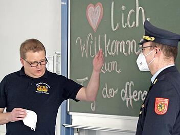 Wie kleiden sich Feuerwehrleute? Gruppenführer Stephan Ludwig (links) erklärt es den Zuschauern im Livestream mit Hilfe der Uniform von Stadtbrandinspektor Florian Höfner.