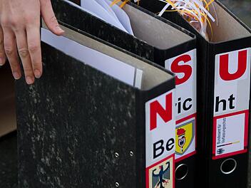 Ein Teilnehmer einer Kundgebung vor dem sächsischen Landtag in Dresden stellt am 05.11.2012 vor der Anhörung des ehemaligen Landespolizeipräsidenten von Sachsen im Landtags-Untersuchungsausschuss zur Zwickauer Neonazi-Terrorzelle drei Aktenordner mit der Aufschrift "NSU Bericht" auf, aus denen geschreddertes Papier heraus schaut. Foto: Arno Burgi, dpa