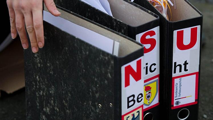 Ein Teilnehmer einer Kundgebung vor dem sächsischen Landtag in Dresden stellt am 05.11.2012 vor der Anhörung des ehemaligen Landespolizeipräsidenten von Sachsen im Landtags-Untersuchungsausschuss zur Zwickauer Neonazi-Terrorzelle drei Aktenordner mit der Aufschrift "NSU Bericht" auf, aus denen geschreddertes Papier heraus schaut. Foto: Arno Burgi, dpa