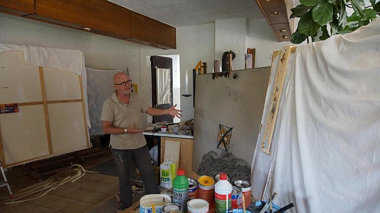 Ernst J. Herlet zeigt eine seiner Arbeiten. Die verhüllten Bilder will er erst im kommenden Jahr präsentieren. Foto: Arkadius Guzy