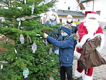 Während sich der Nikolaus (Dunja Pechtold) auf die Gabenverteilung vorbereitet, kümmern sich Jette Hein (10), Mutter Daniela und Ortssprecher Werner Kölbel ums Schmücken des ersten "Neusicher Lichterbaums".  Foto: Klaus Oelzner