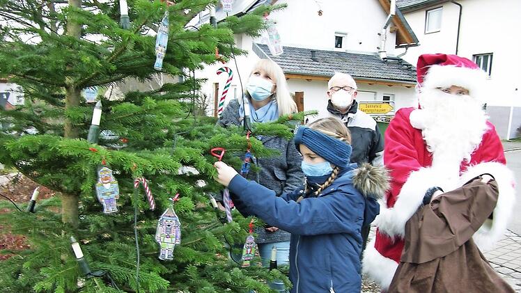 Während sich der Nikolaus (Dunja Pechtold) auf die Gabenverteilung vorbereitet, kümmern sich Jette Hein (10), Mutter Daniela und Ortssprecher Werner Kölbel ums Schmücken des ersten "Neusicher Lichterbaums".  Foto: Klaus Oelzner