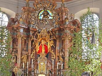 Mit strahlenden Augen führt Annette Urban als zertifizierte Kirchenführerin die Besucher durch die Wallfahrtskirche Mariä Geburt Glosberg. Im Hochaltar befinden sich ganz oben das bunte Glasfenster "Glorie" und in der Mitte des Hochaltars das Marien-Gnadenbild, welches seit 1727 verehrt wird.  Foto: K.- H. Hofmann