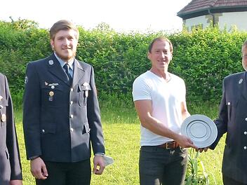 Stefan Beierlein (rechts) wird von Bürgermeister Andreas Carl (links daneben) der Zinnwappenteller der Gemeinde Weitramsdorf im Beisein der neu gewählten Kommandanten Jochen Ambrassat (links) und Jan Schumann überreicht.