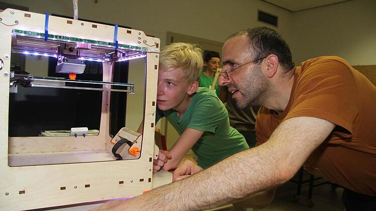 Gleichermaßen fasziniert schauen Lehrer Wolfgang Lormes und Patrick Bär der Entstehung des Roboters zu. 39 Minuten braucht der Drucker für die kleine Figur. Foto: Sonja Adam