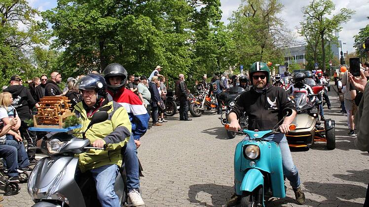 Motorradfahrer sammeln bei "Toy Run" Spenden für kranke Kinder in Bamberg. Männer auf Mopeds, viele Zuschauer und Bäume im Hintergrund.