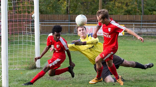Obersdorfs Keeper Matthias Wei&szlig; kann einen Freisto&szlig; nicht festhalten, aber die Kronacher Daniel Kebede (rotes Trikot, links) und Andre Zapf (rechts) schaffen es nicht, den Ball &uuml;ber die Torlinie zu bef&ouml;rdern.  Foto: Wei&szlig;