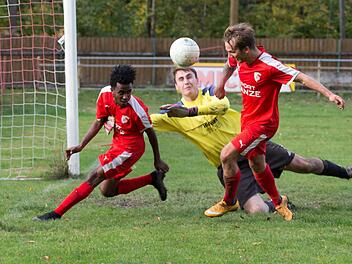Obersdorfs Keeper Matthias Wei&szlig; kann einen Freisto&szlig; nicht festhalten, aber die Kronacher Daniel Kebede (rotes Trikot, links) und Andre Zapf (rechts) schaffen es nicht, den Ball &uuml;ber die Torlinie zu bef&ouml;rdern.  Foto: Wei&szlig;