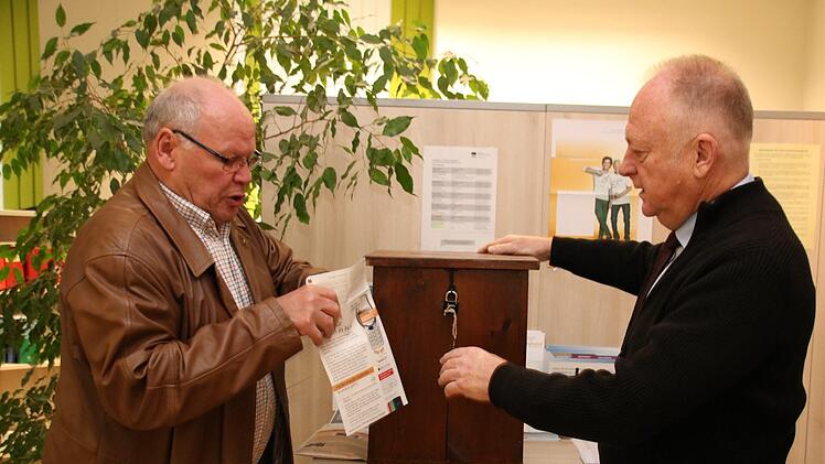 Albert Laudensack (links) tütet ein Handy ein. Nach Rücksprache mit Bürgermeister Helmut Blank sind im Rathaus und im Schloss Wahlurnen als Spendenboxen für alte Handys aufgestellt worden. Thomas Malz