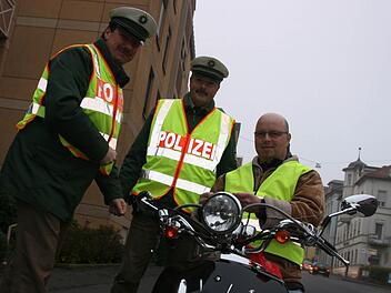 Daniel Mohr (rechts) fühlt sich jetzt sicherer auf seinem Vespa-Roller. Mit der Warnweste, die ihm Matthias Kleren (links) und Martin Kaiser überreichten, wird er im morgendlichen Berufsverkehr besser erkannt. Fotos: Paul Ziegler