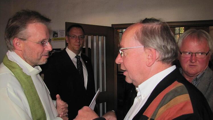 Der römisch-katholische Pastoralreferent em. Georg Bischlager begrüßt den neuen alt-katholischen Pfarrer Hans-Jürgen Pöschl.Im Hintergrund sind Bürgermeister Thomas Nowak und Eduard Adam, weiland Kirchenvorstand in St. Nikolaus zu sehen. Foto: Martin Koch