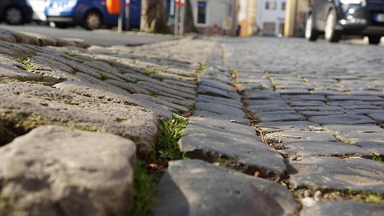 Das Pflaster rings um die Asphaltfläche ist uneben.