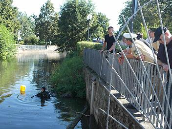 Zusammen mit Beamten der Kulmbacher Inspektion beobachten die Taucher der Nürnberger Bereitschaftspolizei (mit schwarzen T-Shirts) die Arbeit ihrer Kollegen im Weißen Main hinter der Stadthalle. Im Lauf des Tages gesellen sich immer wieder Schaulustige hinzu. Fotos: Peter Müller