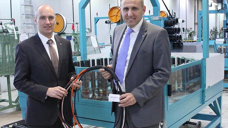 Delfingen-Juniorchef Gérald Streit (links) und Geschäftsführer Matthias Littig mit einigen durch textile Flechtsysteme geschützten Kabeln vor einer der Flechtmaschinen in Marktrodach  Fotos: Friedwald Schedel