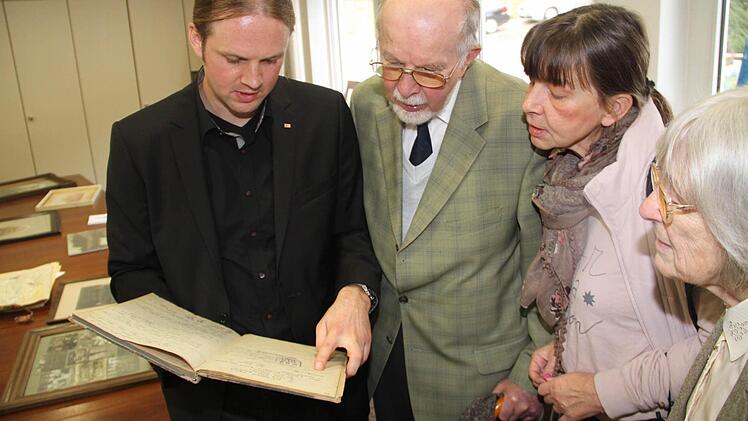 Der stellvertretende Kreisgeschäftsführer Stephen Bauersachs (li.) blättert mit Besuchern im historischen Gästebuch des Roten Kreuzes aus der ersten Hälfte des 20. Jahrhunderts.