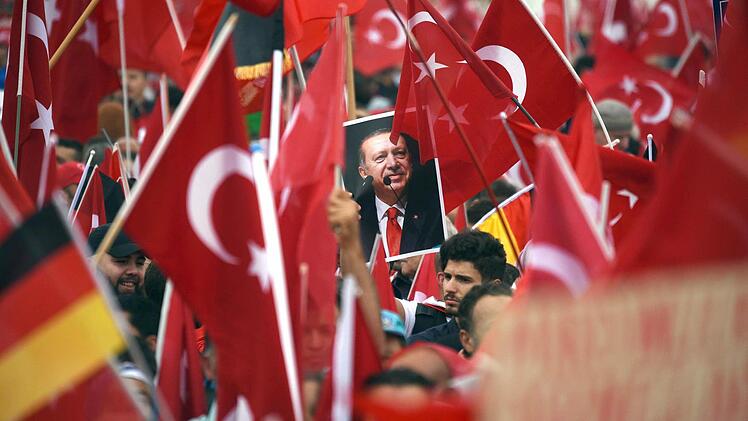 Anhänger des türkischen Staatspräsidenten Erdogan halten am 31. Juli in Köln Fahnen hoch. Foto: Henning Kaiser, dpa