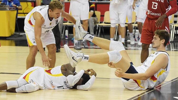 Die Deutschen am Boden. Dennis Schröder (links) und Tibor Pleiß liegen am Boden. Kapitän Heiko Schaffartzik bückt sich zu seinem Teamkollegen. Foto: Rainer Jensen/dpa